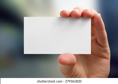 Hands Holding A White Business Visit Card, Gift, Ticket, Pass, Present Close Up On Blurred Blue Background. Copy Space