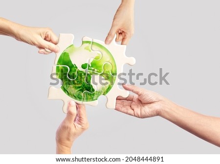 Hands holding white jigsaw with globe glass earth with green grass field in side on light pastel background, Friendly World Sustainable Environment Natural Day and Save our Earth Concept