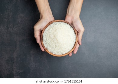 Hands Holding A Wooden Bowl Of Rice Grains For Zakat, Islamic Zakat Concept. Muslims To Help The Poor And Needy. Conceptual Shoot For Property, Income, And Fitrah Zakat.