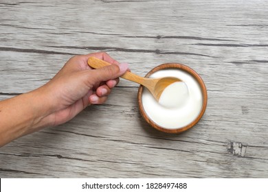 Hands Holding Wooden Spoon Yogurt In A Wooden Cup With Copy Space On Wood  Background