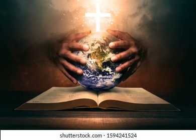 Hands holding the world on a open bible. 