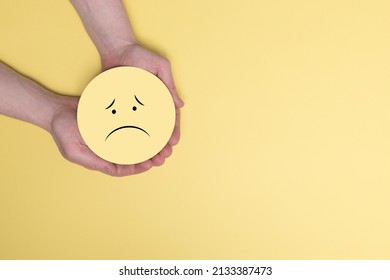 Hands holding yellow sad smile, bad feedback rating, negative customer review, bad experience, unsatisfied survey, mental health assessment, child wellness concept, 