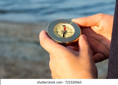 Hands holds a compass indicating the direction of the background of the sea - Shutterstock ID 721520563