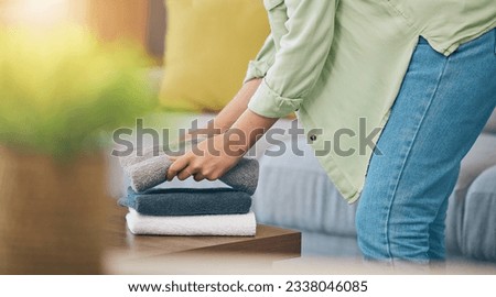 Hands, home and fold laundry on table for hygiene, cleaning and soft clothes for housework in living room. Woman, fabric and cotton towel on desk for organized house, service and routine in apartment