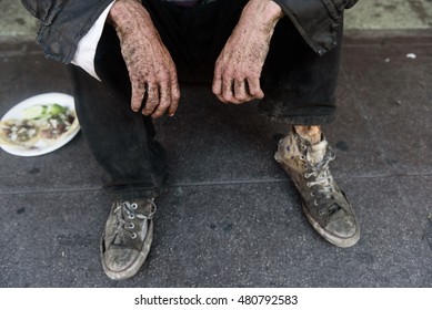 The hands of homeless man sitting on the sidewalk