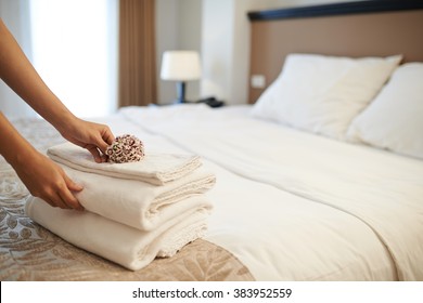 Hands of hotel maid putting flowers on the stack of towels - Shutterstock ID 383952559