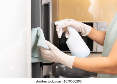 Hands Of A House Wife In Protective Gloves With Microfibre Cleaning Cloth And 70% Alcohol Spray Disinfecting Product, She Cleaning The Refrigerator Door Handle In The Kitchen. Disinfection Covid 19