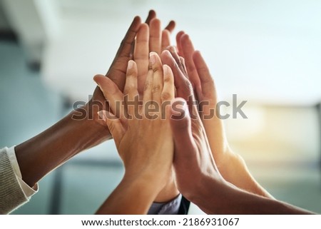 Hands, huddle and high five while a group of diverse businesspeople celebrate and motivate each other at the workplace. Colleagues winning and achieving success through teamwork and collaboration