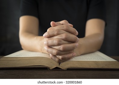 Hands of a human in prayer on a Holy Bible . religion concept.