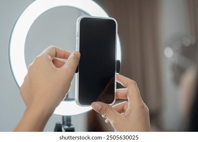 Hands of influencer adjusting smart phone on ring light at home.  Influencer and person with package, record video on social media and content creation, ring light and phone concept. - Powered by Shutterstock