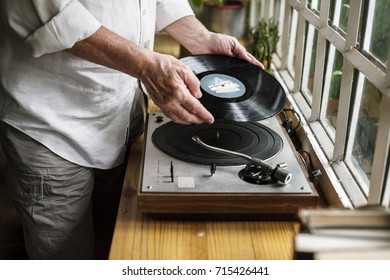 Hands insert vinyl disc to turntable player