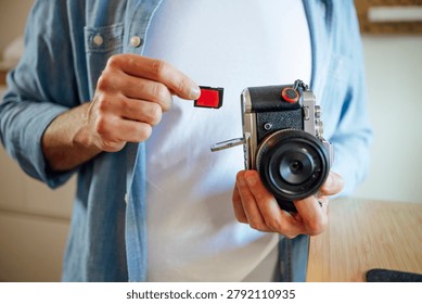 Hands inserting a memory card into an open slot on a mirrorless camera