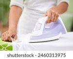 Hands, iron and laundry for closeup in home with tools, working and cleaning service for wrinkles in fabric. Person, cleaner and machine for clothes with housekeeping, board and press at apartment