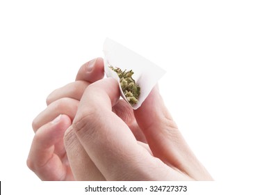 Hands isolated on white background rolling a cannabis joint. Smoking marijuana addiction. 