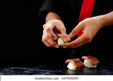 Hands of japanese chef holding unagi sushi.