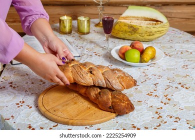 The Hands Of A Jewish Woman Break The Challah After The Blessing During The Shabbat Meal Next To Burning Candles And A Glass Of Wine. Horizontal Photo