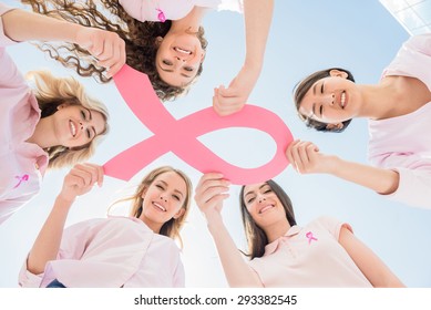 Hands joined in circle holding breast cancer struggle symbol.