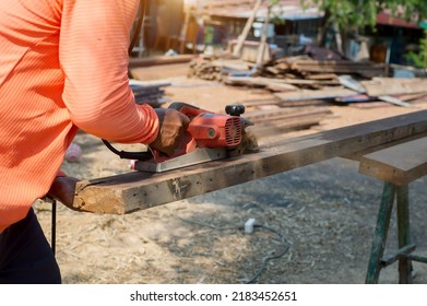 Hands of a joiner with an electric planer. Flying shavings, wooden board. The work of a professional. Woodwork. - Powered by Shutterstock