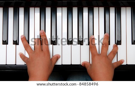Hands of kid on piano keyboard