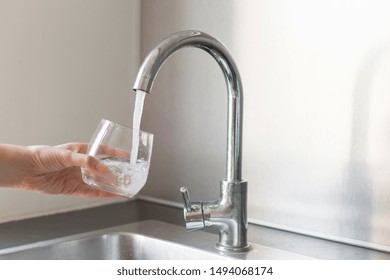 Hands In The Kitchen Taking A Glass Of Water At The Kitchen Sink At Home.