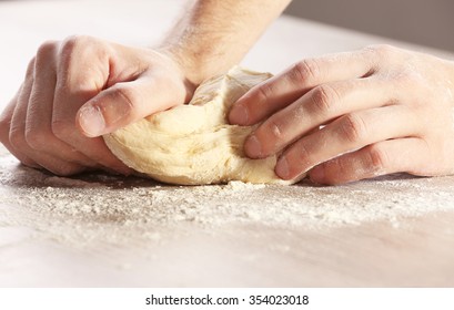Hands kneading dough for pizza on the wooden table, close-up - Shutterstock ID 354023018