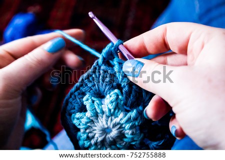 Hands knitting with blue wool