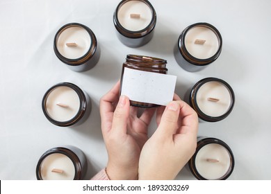 Hands Labelling A Handmade Ecological And Vegan Soya Wax Candle. Space For Text On The Label. Amber And Opaque Container. Candle Making Utensils. Cruelty-free. Content For Digital Marketing