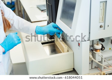 Hands of laboratory assistant loading sample tubes for coagulation test analysis.