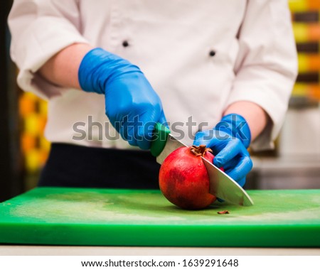 Hands in latex gloves cutting pomegranate