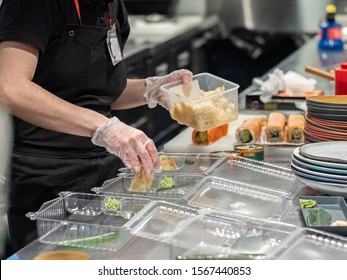 Hands In Latex Gloves Spread The Ingredients For Japanese Rolls In Plastic Disposable Containers. Food Delivery During The Coronavirus Epidemic. Compliance With Hygiene Measures.