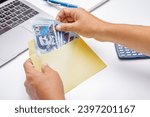 Hands of a latin man counting peruvian soles bills in a yellow envelope on a white desk