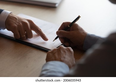 Hands of lawyer pointing at paper for businessman signing contract. Solicitor, legal advisor helping mature client to fill up document, medical insurance form, will, affixing signature. Paperwork