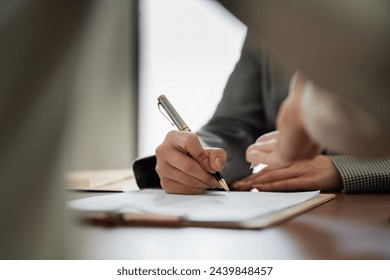 Hands of lawyer pointing at paper for businessman signing contract. legal advisor helping mature client to fill up document - Powered by Shutterstock