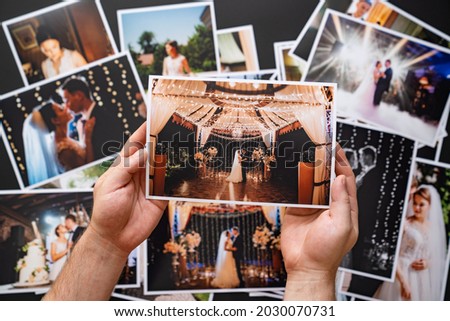 hands lay out a printed copy of the wedding photos. the result of the photographer's work at the wedding. printed products. a photo session of the bride and groom.