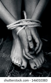 Hands and legs of a missing kidnapped, abused, hostage, victim woman tied up with rope. Concept of restricted, trapped,help, struggle, locked, smuggling, trafficking and human rights. Copy space
