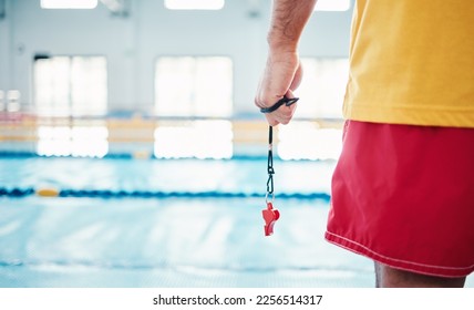 Hands, lifeguard and whistle by swimming pool for water safety, security or ready for rescue indoors. Hand of expert swimmer holding signal tool for warning, safe swim or responsibility for awareness