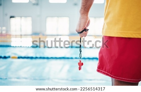 Hands, lifeguard and whistle by swimming pool for water safety, security or ready for rescue indoors. Hand of expert swimmer holding signal tool for warning, safe swim or responsibility for awareness