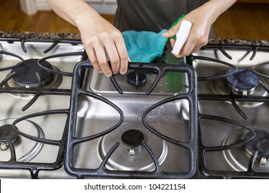 Hands Lifting Front Grill Of Stove Top Range With Spray Bottle In Hand