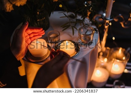 Hands light a candle. Decoration, arrangement and location preparation for surprise marriage proposal. Romantic candlelight dinner at terrace restaurant at night. Place for date or engagement in park.
