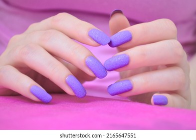 Hands with lilac manicure isolated on pink background.