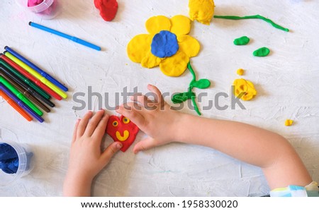 Hands of little girl making flower and sun and other  from colorful clay dough, plasticine, Home Education game with clay. Early development concept. Educational and entertaining classes with children