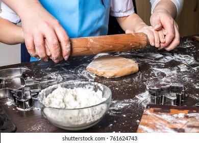 Hands of little girl sheeting dough with rolling pin. Christmas baking preparation. Child's hands with a rolling pin baking Christmas gingerbread cookies. Christmas cookies concept. Top view.