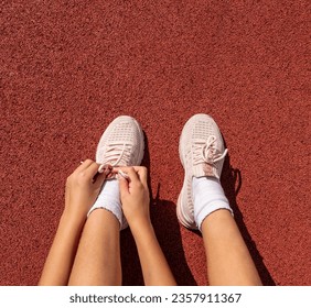 Hands of a little girl, tying shoelaces on sneakers on a running field, sports concept, sports kids, rest after sports - Powered by Shutterstock