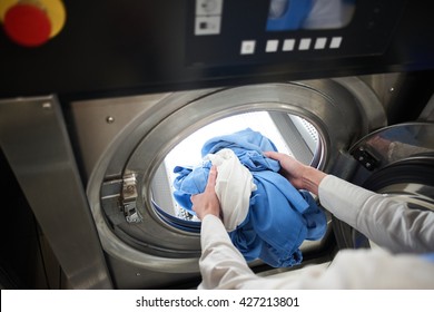 Hands to load the Laundry in the washing machine at the dry cleaners