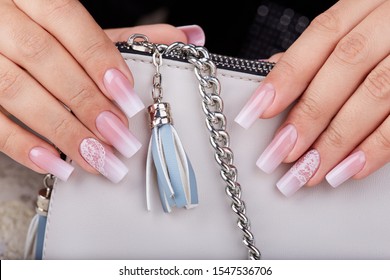 Hands and long artificial manicured nails and ombre gradient design in pink   white colors