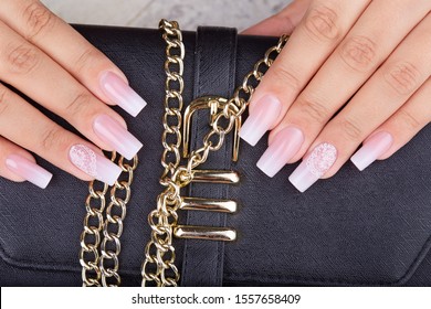 Hands and long artificial manicured nails and ombre gradient design in pink   white colors