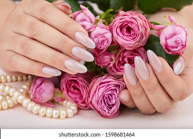 Hands and long artificial manicured nails colored and nail polish and silver glitter   pink roses