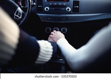 Hands of lovers together in a car close up