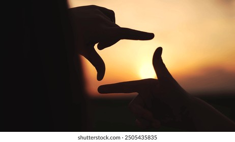 hands make camera from fingers at sunset. happy family kid dream concept. hands in the foreground fold the figure from the fingers. camera of fingers stacked in a field at sunset lifestyle - Powered by Shutterstock