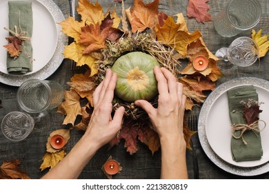 Hands makes autumn arrangement with pumpkin for thanksgiving holiday feast. Autumnal table setting for holiday dinner, top view.  - Shutterstock ID 2213820819